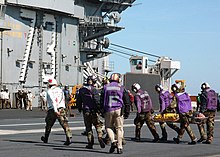 George Washington personnel carry injured personnel across the ship's flight deck after four personnel were rescued from the burning merchant fishing vessel, Diamond Shoal. US Navy 030202-N-6278J-001 Rescue at sea aboard the USS George Washington CVN 73.jpg