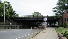 The railroad bridge over Washington Street in 2011, at which time the station entrance was planned to be under the bridge Washington Street MBTA rail bridge from Joy Street, June 2011.jpg