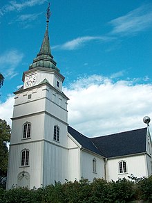 Foto antiga de uma igreja branca com uma torre de relógio e pináculo