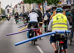רוכבי אופניים מדגימים מרחק עקיפה בטוח עם ספוגים דמויי איטריה לבריכה. ברלין, 2019