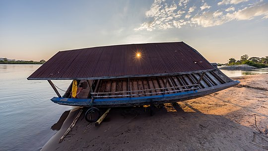 Contre-jour photograph of the careening of a pirogue at sunset with sunlight through a hole in its roof Si Phan Don Laos