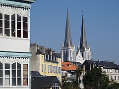 Цветная фотография двух шпилей церкви, выступающих над крышами.