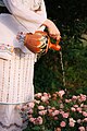 Folk girl watering flowers in garden