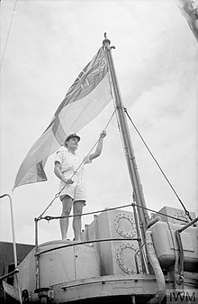 White Ensign flying from HMS Foxhound, 1943. HMS FOXHOUNDS'S FINE FIGHTING RECORD FROM ICELAND TO THE BAY OF BENGAL. AUGUST 1943, FREETOWN. THE BRITISH DESTROYER FOXHOUND CLAIMS TO HAVE SET UP A RECORD BY STEAMING 240,000 MILES SINCE THE WAR BEGAN. A18774.jpg