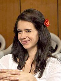 Koechlin in a white dress smiling at the camera