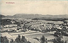 Arial photograph of a small town surrounded by mountains and agricultural fields.