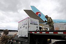 Two members of the 175th Wing of the Maryland Air National Guard unload crates containing COVID-19 tests from an Korean Air plane