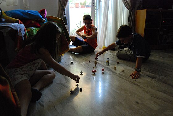 Children trying to keep a number of spinning tops spinning simultaneously.