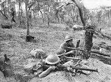 Soldiers with rifles and sub-machine guns man a defensive line