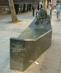 A low rectangular public monument, with a bust of Wilde's face built into one raised end, at the other at seat that one straddles to experience being in conversation with Wilde.