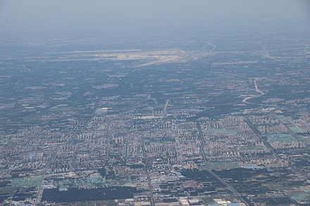 Aerial view of downtown Langfang (below) and Beijing Daxing International Airport in July 2019