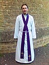 Stole crossed over the chest in the manner of an Anglican priest. Note that this is unusual, most wearing it uncrossed. Anglican priest vested in an alb, cincture and purple stole.jpg