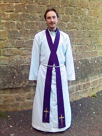 Some clergy may wear vestments such as the alb (pictured) when celebrating rites such as baptism Anglican priest vested in an alb, cincture and purple stole.jpg