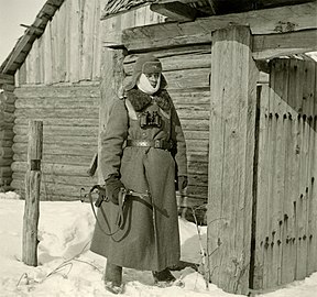 Photographie en noir et blanc d'un soldat montant la garde sous la neige.