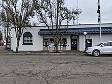 A white, single-level commercial building with a blue awning and trim