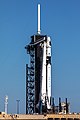 Raketa Falcon 9 s lodí Crew Dragon na startovací rampě.