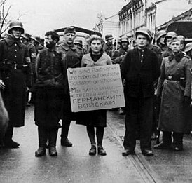 Мария Брускина перед казнью (на фото — в центре со щитом на груди, на щите надпись на немецком и русском языках: «Мы партизаны, стрелявшие по германским войскам»), 26 октября 1941 года.
