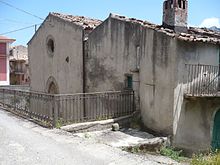 Photographie de la modeste façade d'une église au toit méditerranéen et en mauvais état.