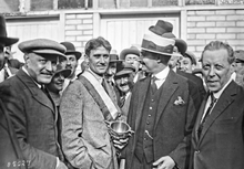 Fotografia in bianco e nero di diversi uomini attorno a un trofeo.