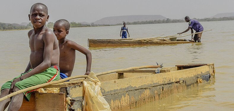 Le lac Bam, situé au Burkina Faso, est le plus grand réservoir naturel d'eau de surface du pays, avec un bassin versant de 2 610 km2 s'étendant de Kongoussi à Bourzanga. Ce site joue un rôle crucial en fournissant la subsistance à des milliers de personnes dans la province de Bam, grâce à l'agriculture maraîchère et à la pêche. Environ 800 pêcheurs y trouvent leur moyen de subsistance, et cette tradition de pêche se transmet de génération en génération, de père en fils. Il n'est donc pas rare de voir des enfants de pêcheurs à bord des pirogues, partant à la recherche de poissons. Malheureusement, le lac est en train de s'assécher progressivement, ce qui présente un risque sérieux pour les stocks de poissons ainsi que l'approvisionnement en eau nécessaire aux cultures et au bétail. Photographe: Zimèwè Didier