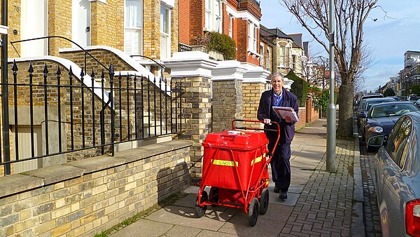 21st-century postman in London delivering mail from a modern mail cart