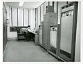 W. W. Youden shown operating SEAC - The control console is pictured at the far end of the room, and the computer proper is shown at left. To the right are pictured several of the external storage units which stored on magnetic tape such information as coded subroutines, instructions to the machine, and numerical data, as well as the entire coded program for a problem and its solution when the problem was completed.