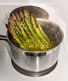 Steam boiling asparagus in a pot