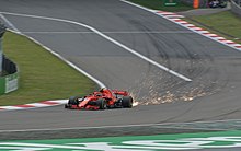 Mobil Scuderia Ferrari berwarna merah dengan garis putih bernomor tujuh yang dikemudikan oleh pembalap Kimi Räikkönen sedang memutari sirkuit pada sesi kualifikasi untuk Grand Prix F1 Tiongkok 2018 di Sirkuit Internasional Shanghai, Tiongkok.