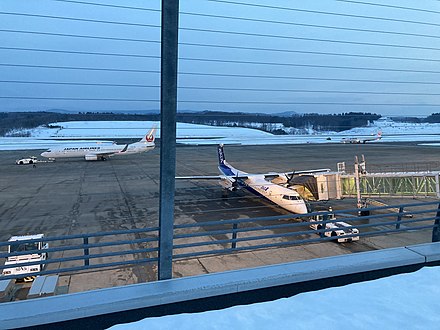 Apron traffic at Aomori Airport: pictured is a De Havilland Canada DHC-8-400 Dash 8 of ANA Wings parked at the gate, a Boeing 737 Next Generation of Japan Airlines during pushback, and an Embraer 190 of J-Air approaching the gate.