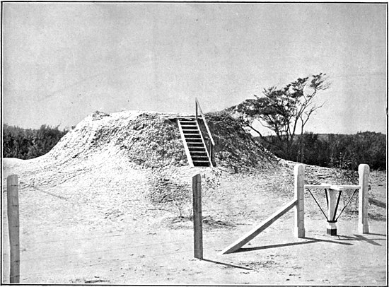 Steps up to the top of a mud volcano so you can view the inside, with a turnstile in the foreground