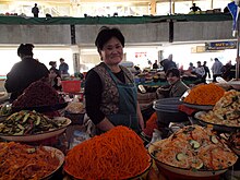 A Koryo-saram vendor in Tashkent, Uzbekistan, with various Koryo-saram banchan, including morkovcha (center) and funchoza (front, right) Food Market in Uzbekistan.jpg