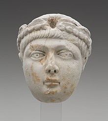 A Miniature portrait head of a a young boy with a full face and short, straight hair. He wears a pearl-edged diadem, which identifies this head as portrait of an Emperor. The head greatly resembles depictions of the Theodosian princes. This marks the identification of the head to be, either Honorius, Arcadius,/Valentinian II.