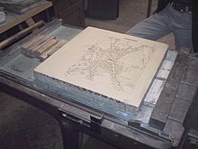A limestone plate with a negative map of Moosburg in Bavaria is prepared for a lithography print. Litography press with map of Moosburg 01.jpg