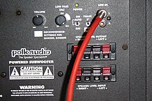 This picture of the rear panel of a Polk subwoofer cabinet shows a low-pass filter adjustment knob. Rear panel of a Polk audio sub-woofer.jpg