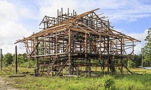 A estrutura de madeira de uma casa em construção, com o chão levantado do chão