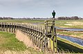 Loopbrug op palen naar havenmond.