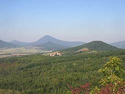 Pohled na Sutomský vrch od jjv. z Košťálu. V pozadí v zákrytu nad sebou Ostrý a Milešovka.