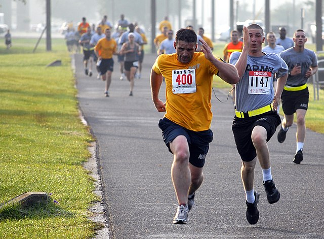 Two men engaging in a sprint finish at the end of a 5-kilometre road running competition