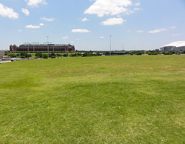 A large portion of the stadium's site is now occupied by an empty field, pictured in 2012. Choctaw Stadium and AT&T Stadium are visible in the backgro