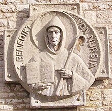 Carving of Saint Benedict of Nursia, holding an abbot's crozier and his Rule for Monasteries (Munsterschwarzach, Germany) Benedikt von Nursia in Muensterschwazach.jpg