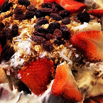 Close up shot of a bionico with strawberries, banana, raisins, shredded coconut and granola
