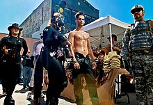 A mixture of kink and leather subcultures mix at the festival. The man on the right may be into uniform and military attire, while the other fair-goers seem to be interested in animal roleplay, including a bare-chested "rider" with his "pony". Folsom Street Fair 2007 - 1681498844.jpg