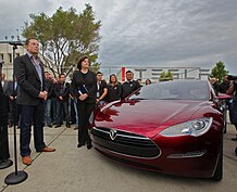 Musk converses with U.S. Senator Dianne Feinstein beside a red Tesla