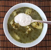 Green borscht with spinach and potatoes, topped with smetana