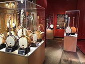 Jazz-Age banjos, American Banjo Museum. In the back is a 1955 Gibson PB-250 banjo, electrified by Les Paul. The instrument is displayed opened up so visitors can see the modifications.