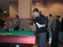 McCready holding cue in front of a pool table