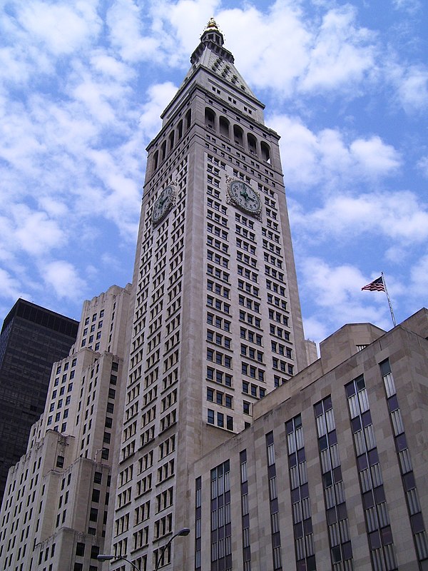 The tower (center) seen from below with clock faces; the east wing is to the right, and the New York Merchandise Mart (far left) and Metropolitan Life