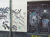 Painted wall and door full of urban graffiti and glued street art; free photo Amsterdam city of Fons Heijnsbroek, January 2022