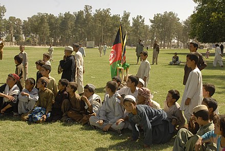 Local children watching a football match at the playground of Ahmad Shah Baba High School.