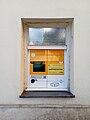 Mały paczkomat w oknie budynku w centrum Pragi (2023)